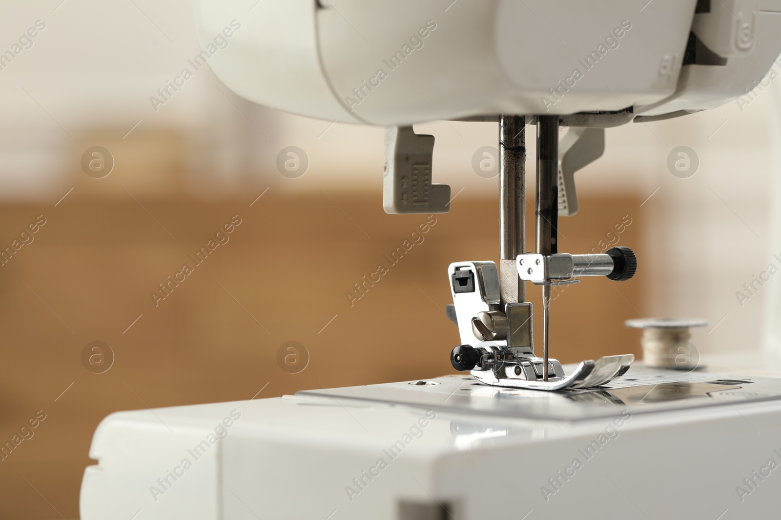 Photo of Sewing machine with thread on blurred background, macro view