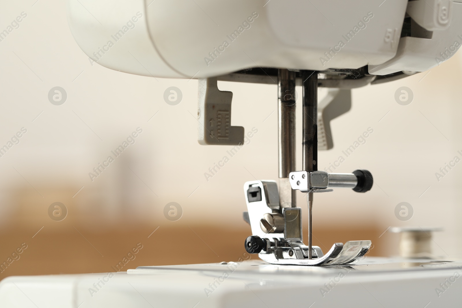 Photo of Sewing machine with thread on blurred background, macro view