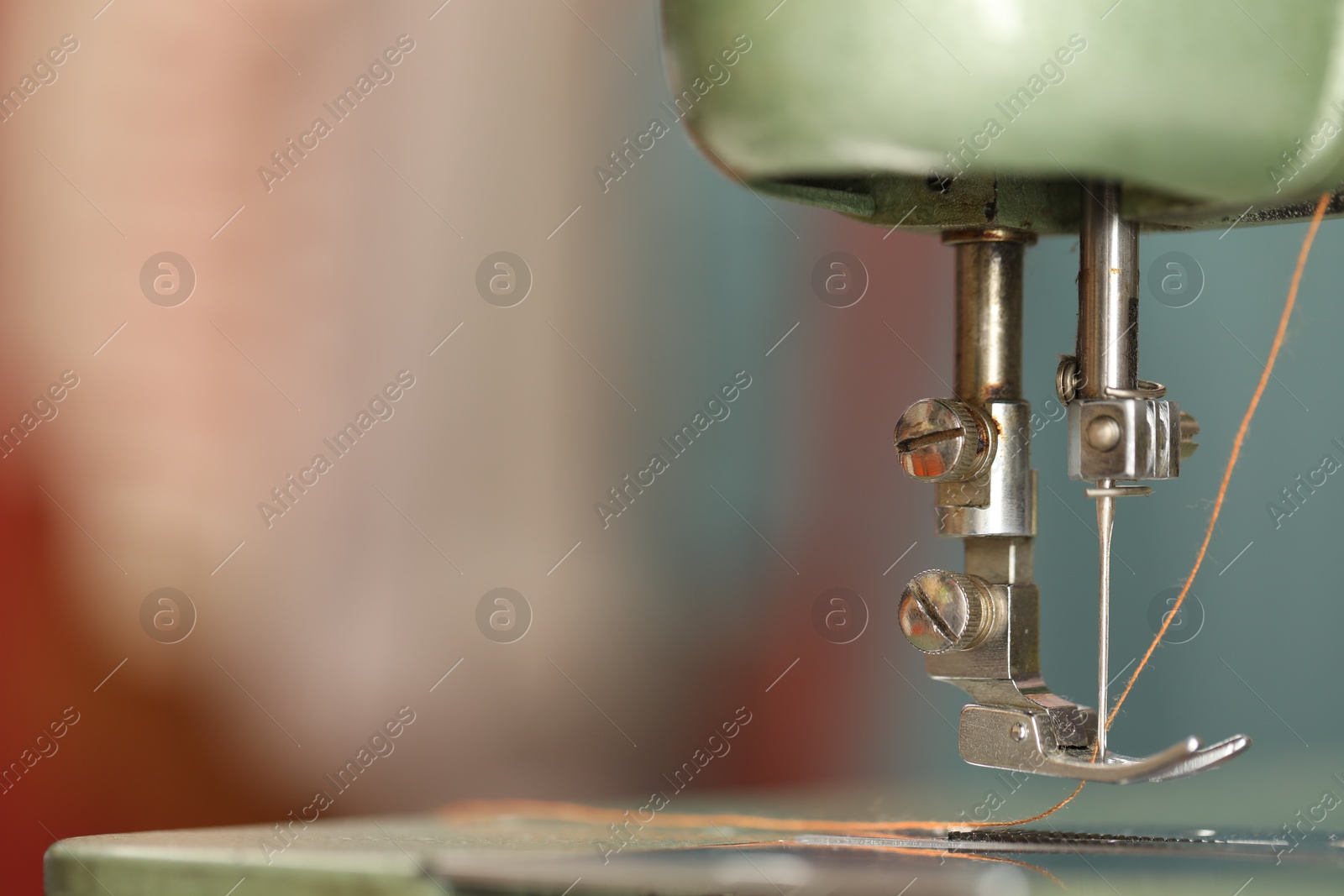 Photo of Vintage sewing machine with thread on blurred background, macro view. Space for text