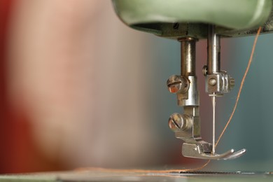 Photo of Vintage sewing machine with thread on blurred background, macro view. Space for text