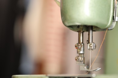 Photo of Vintage sewing machine with thread on blurred background, macro view. Space for text