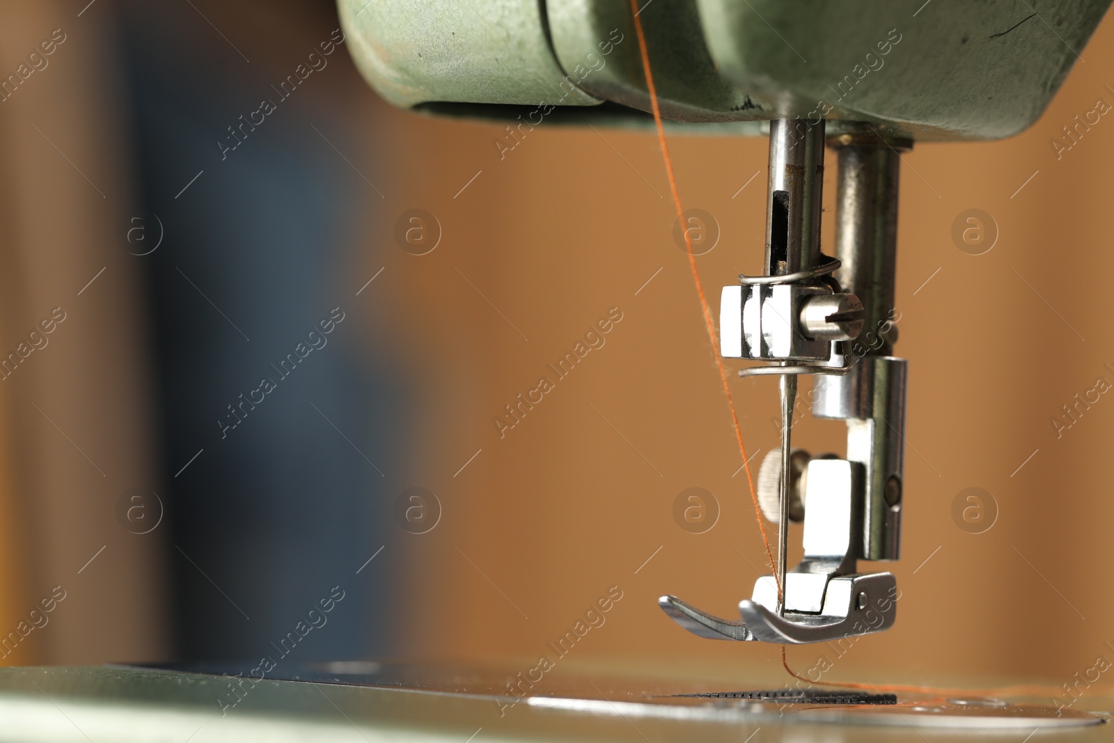 Photo of Vintage sewing machine with thread on blurred background, macro view. Space for text