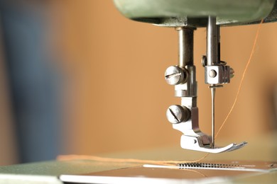 Photo of Vintage sewing machine with thread on blurred background, macro view. Space for text