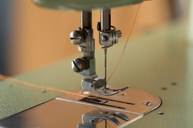 Photo of Vintage sewing machine with thread on blurred background, macro view