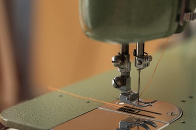 Photo of Vintage sewing machine with thread on blurred background, macro view