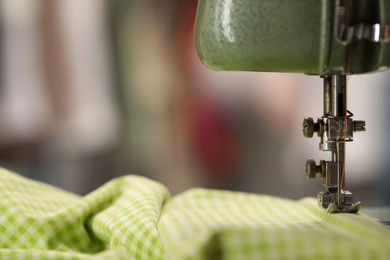 Photo of Vintage sewing machine with thread and fabric on blurred background, macro view. Space for text