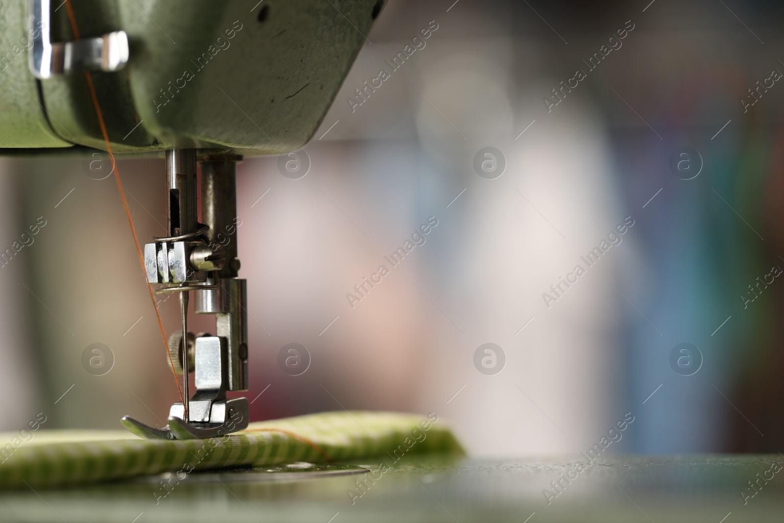 Photo of Vintage sewing machine with thread and fabric on blurred background, macro view. Space for text