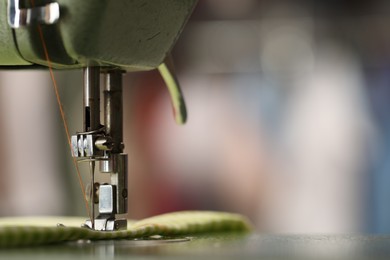 Photo of Vintage sewing machine with thread and fabric on blurred background, macro view. Space for text