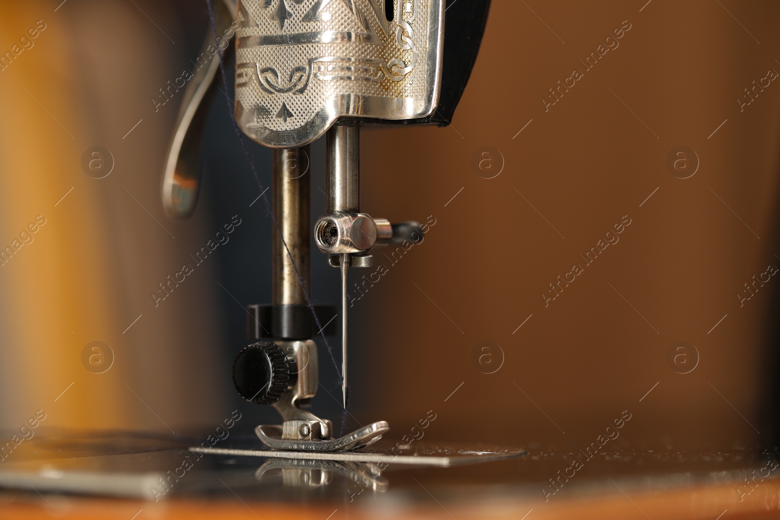 Photo of Vintage sewing machine with thread on blurred background, macro view