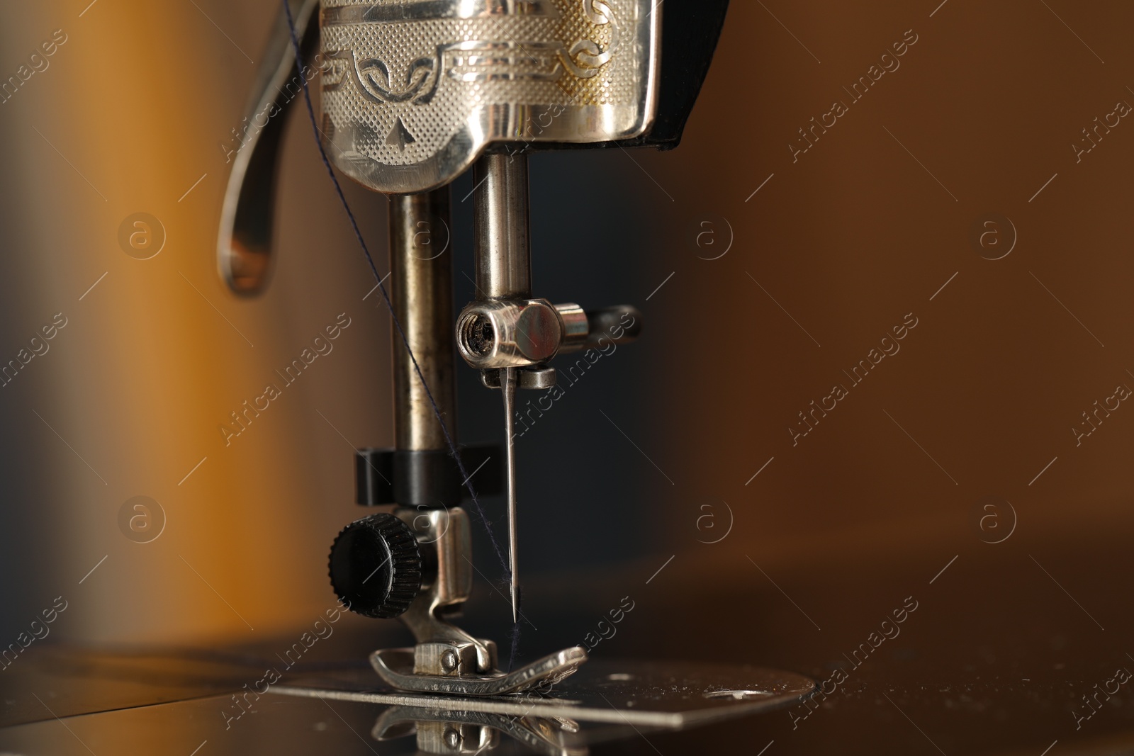 Photo of Vintage sewing machine with thread on blurred background, macro view