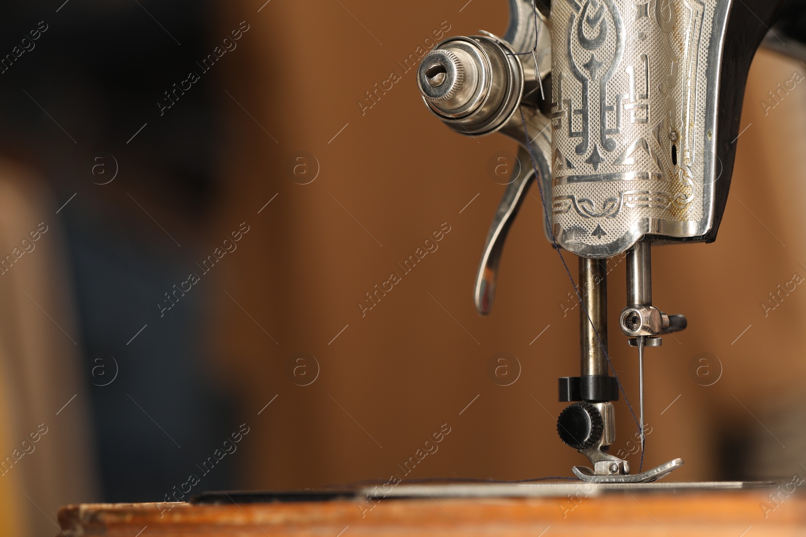 Photo of Vintage sewing machine with thread on blurred background, macro view. Space for text