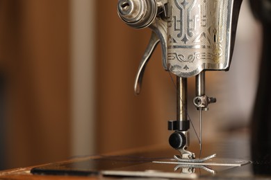 Photo of Vintage sewing machine with thread on blurred background, macro view. Space for text