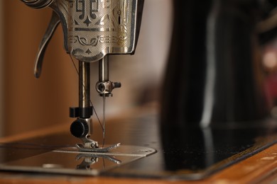 Photo of Vintage sewing machine with thread on blurred background, macro view. Space for text