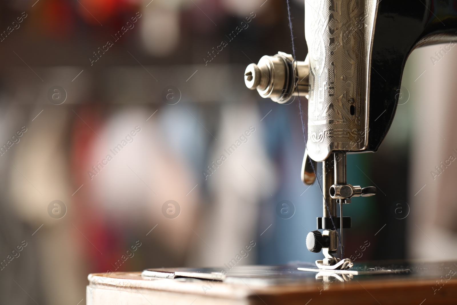 Photo of Vintage sewing machine with thread on blurred background, closeup. Space for text