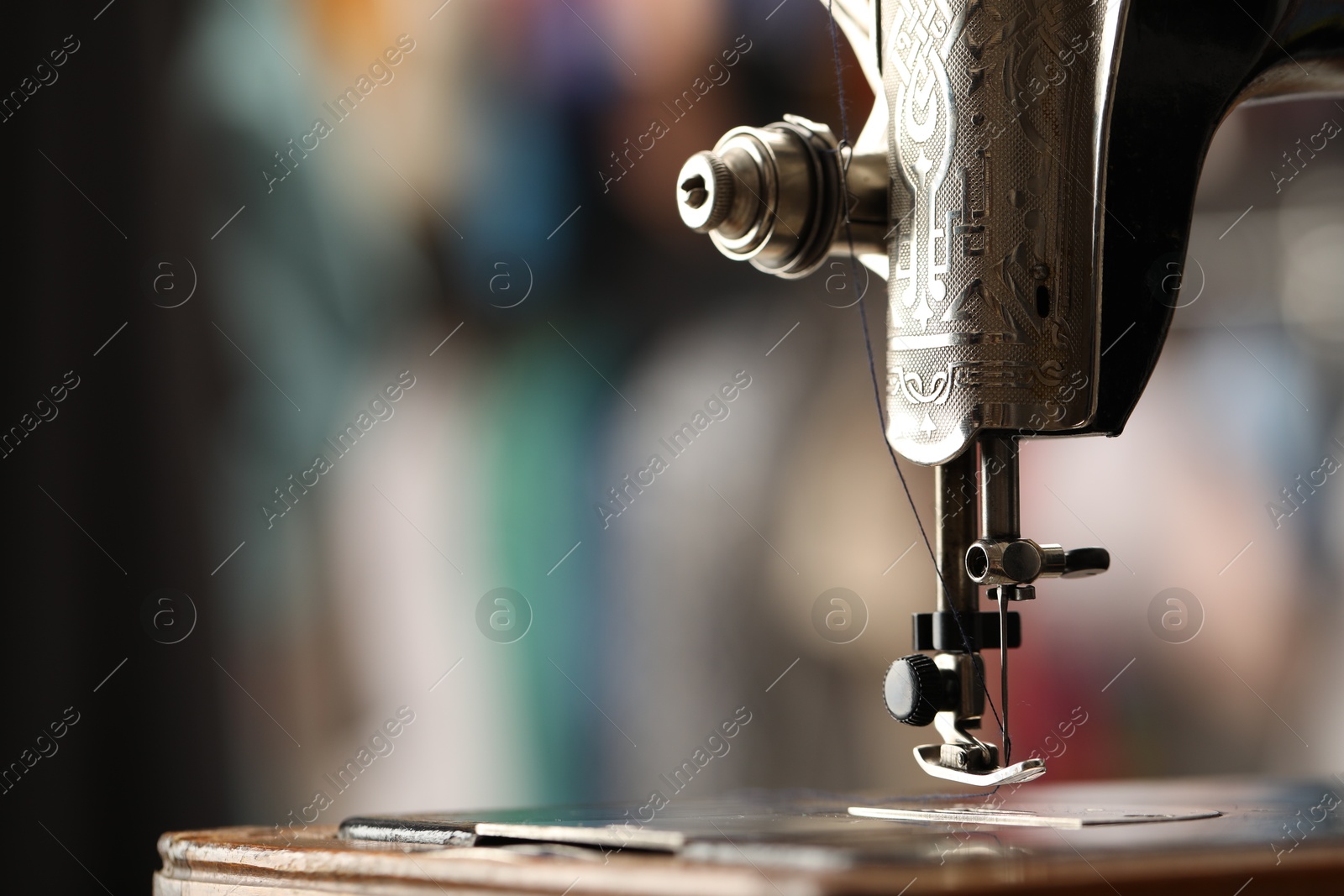 Photo of Vintage sewing machine with thread on blurred background, macro view. Space for text