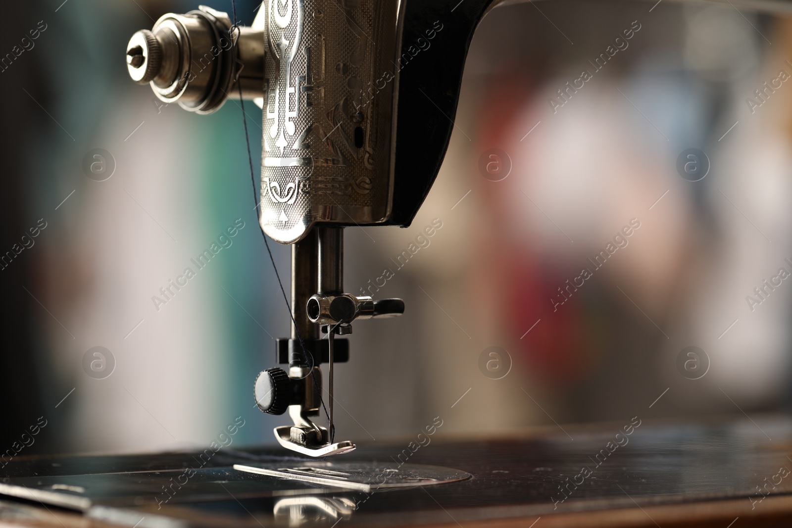 Photo of Vintage sewing machine with thread on blurred background, macro view. Space for text