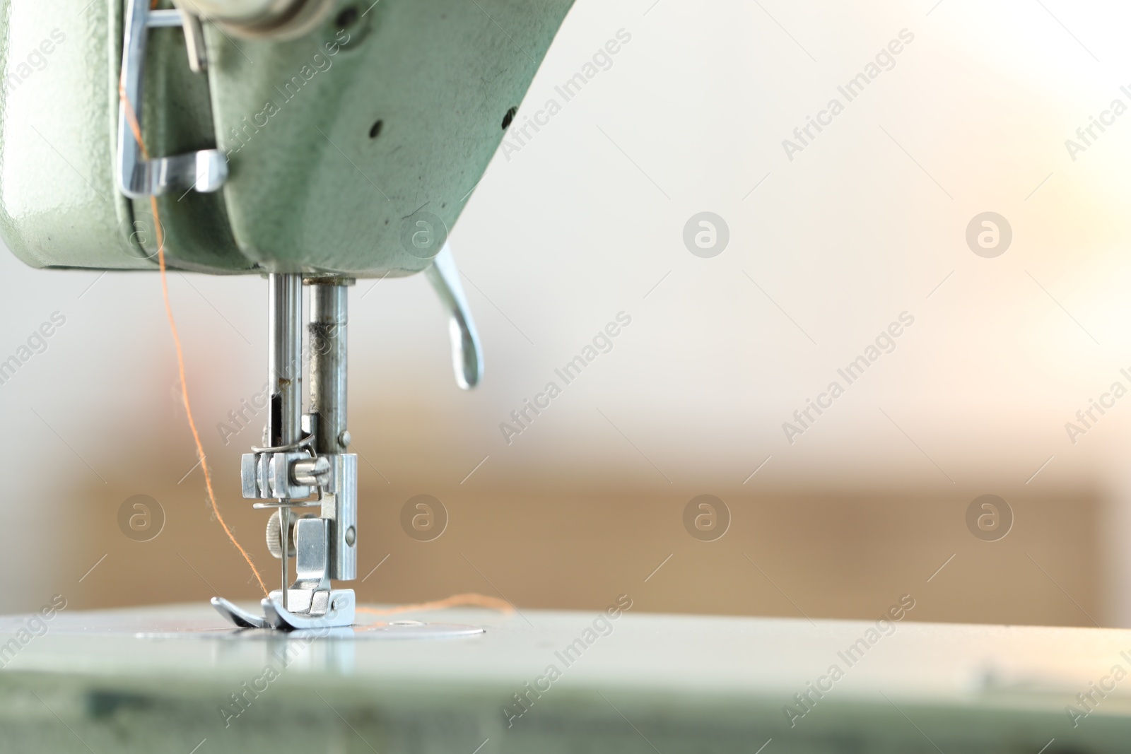 Photo of Sewing machine with thread on blurred background, macro view. Space for text