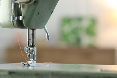 Photo of Sewing machine with thread on blurred background, macro view. Space for text