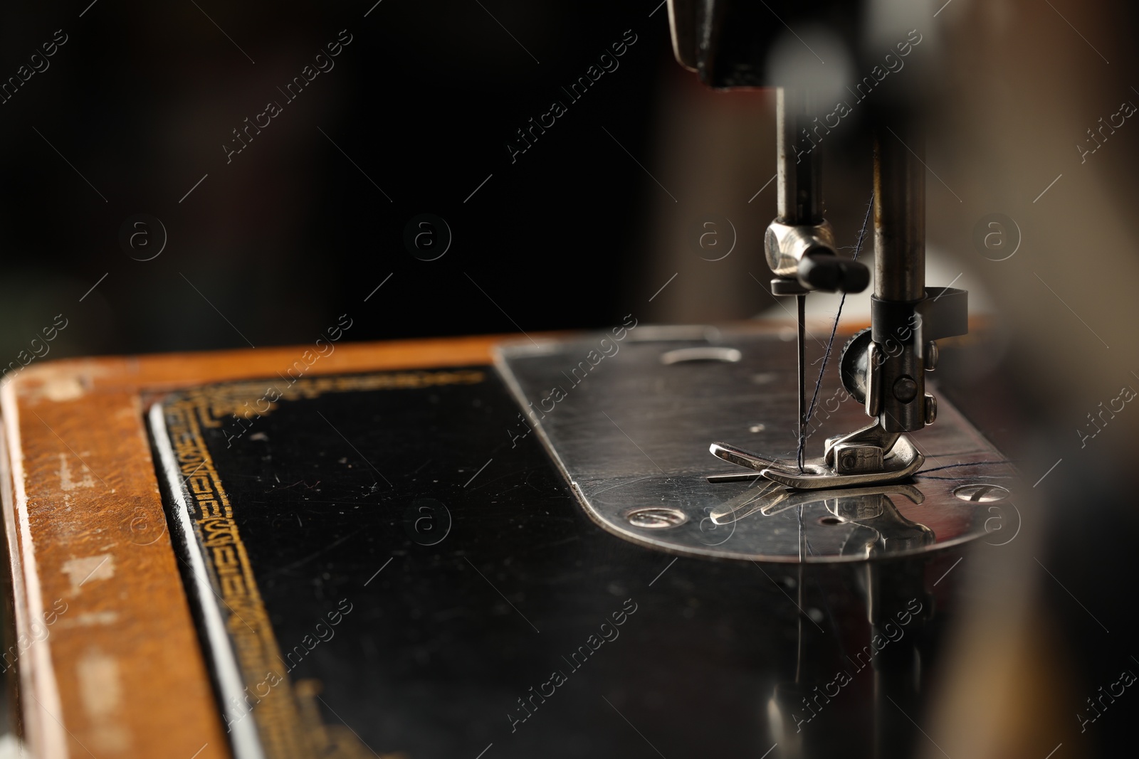 Photo of Sewing machine with thread on blurred background, macro view. Space for text