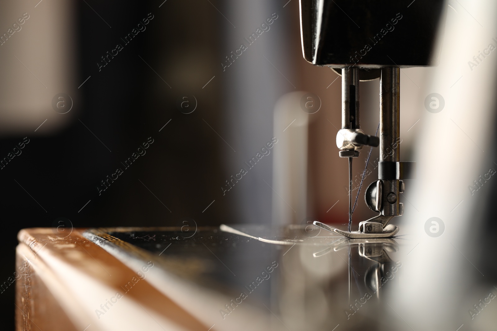 Photo of Sewing machine with thread on blurred background, macro view. Space for text