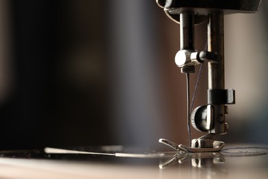 Photo of Sewing machine with thread on blurred background, macro view. Space for text