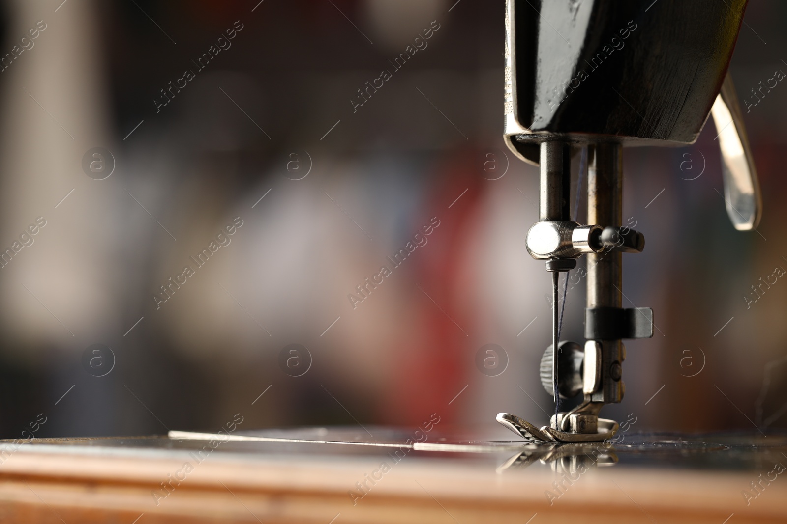 Photo of Sewing machine with thread on blurred background, macro view. Space for text