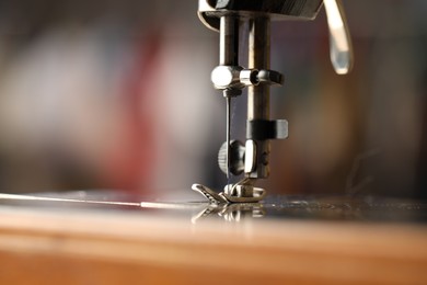 Photo of Sewing machine with thread on blurred background, macro view