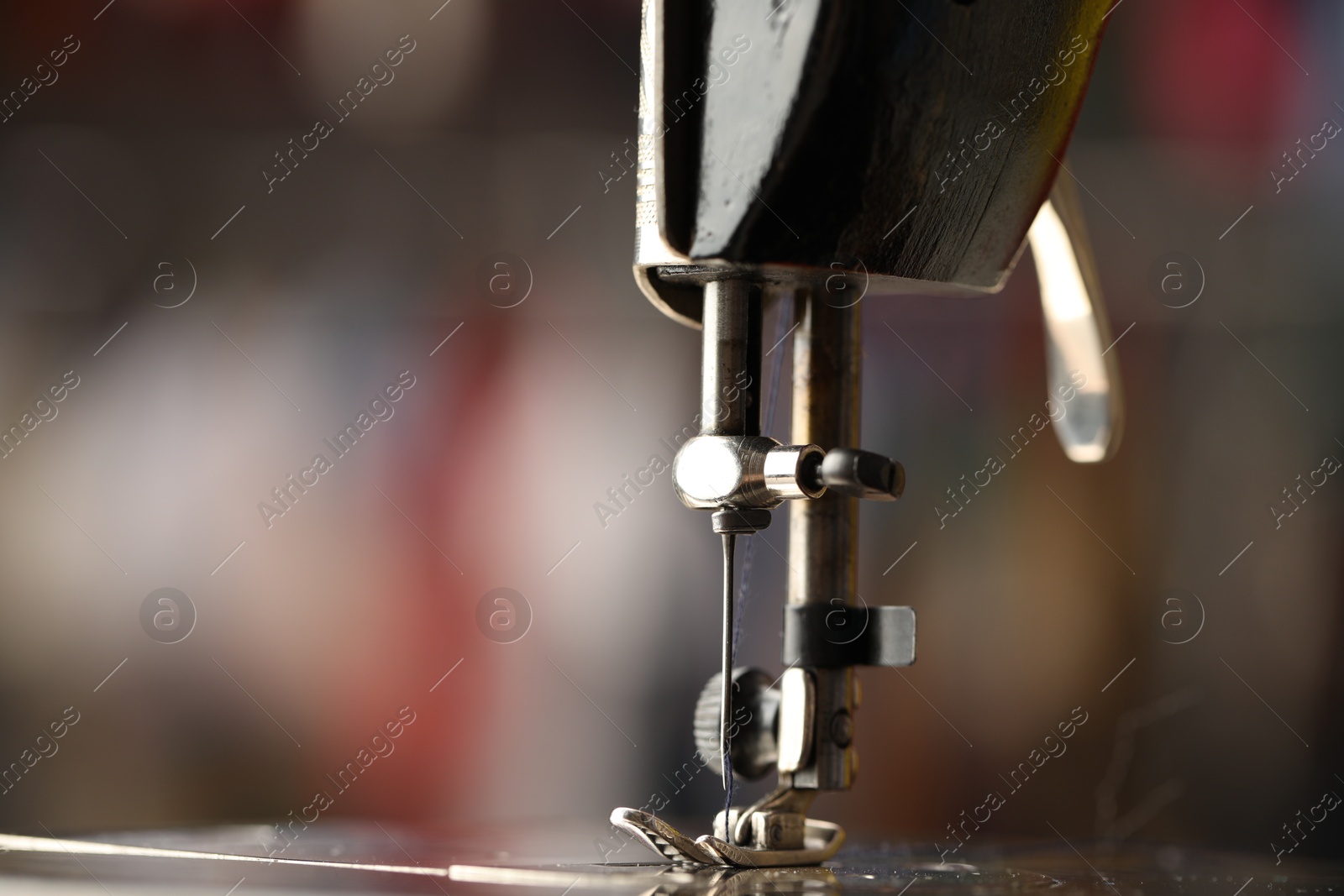 Photo of Sewing machine with thread on blurred background, macro view