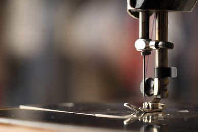 Photo of Sewing machine with thread on blurred background, macro view. Space for text