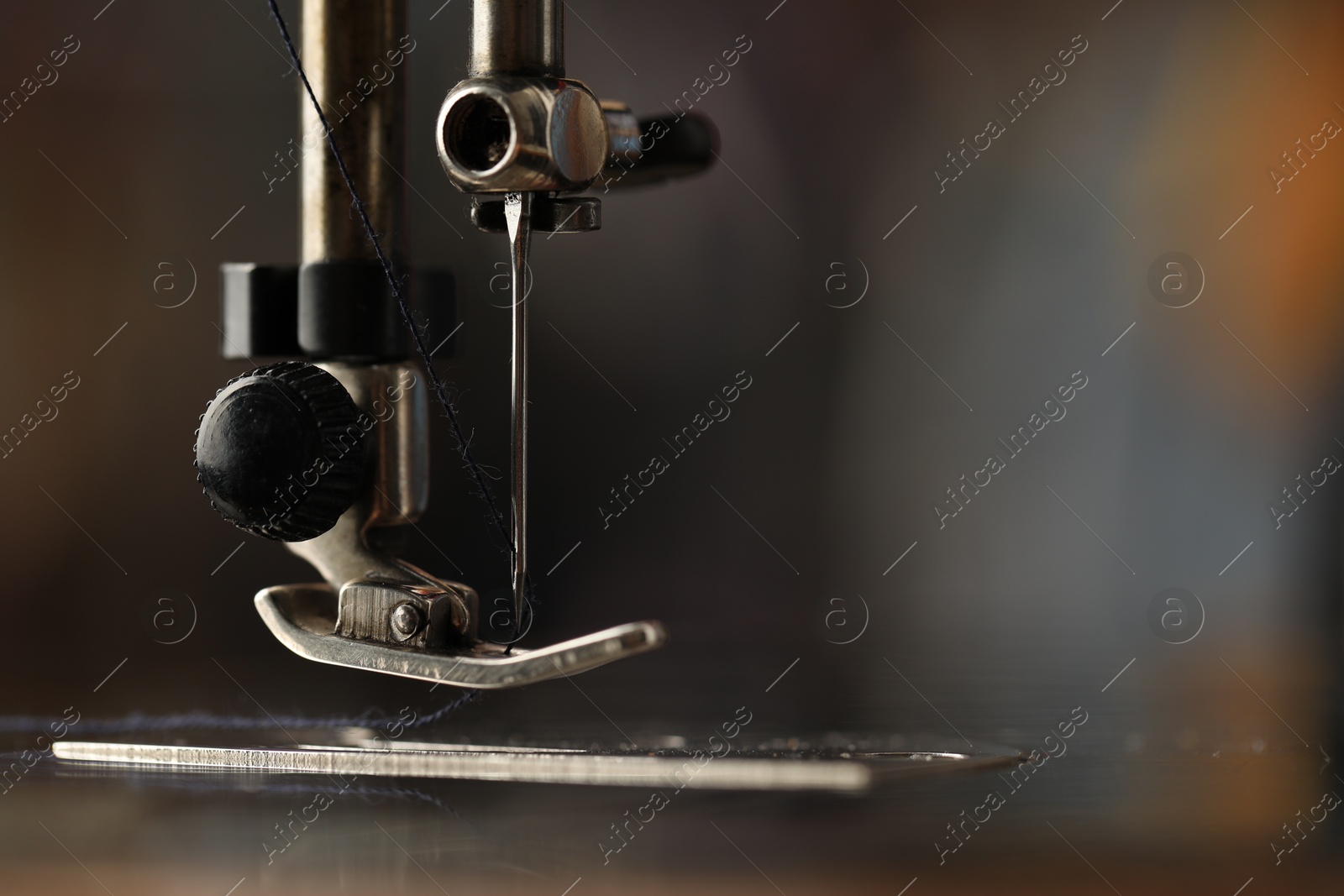 Photo of Sewing machine with thread on blurred background, macro view. Space for text