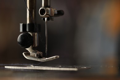 Photo of Sewing machine with thread on blurred background, macro view. Space for text