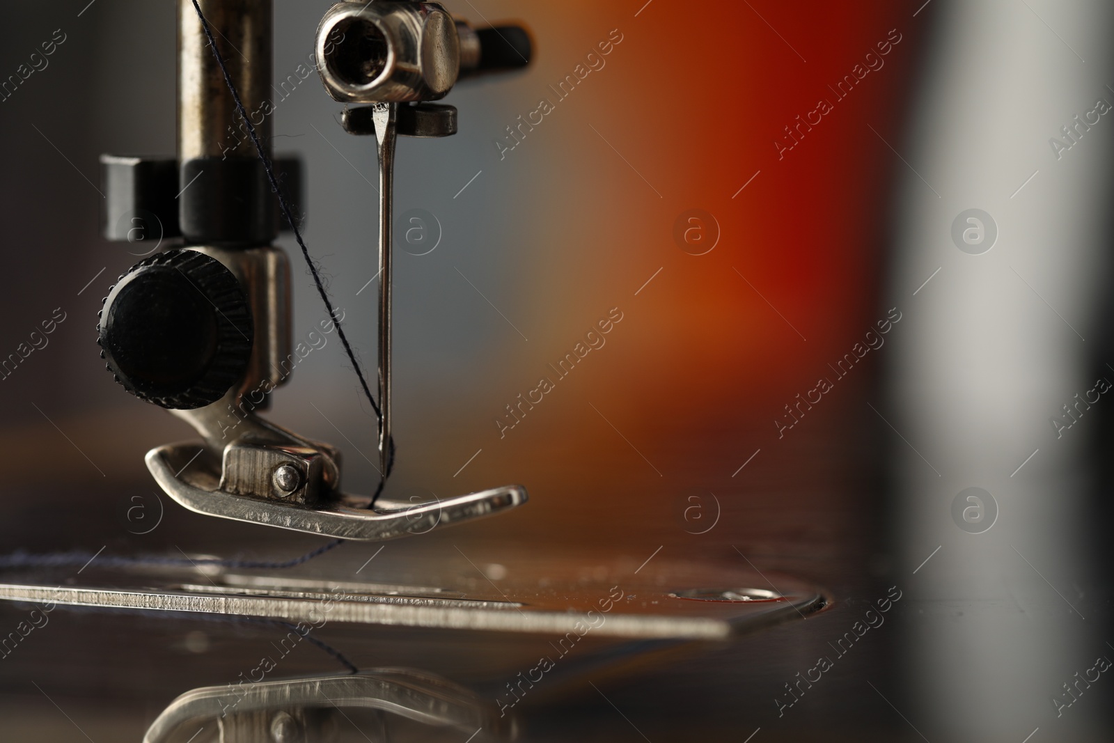 Photo of Sewing machine with thread on blurred background, macro view. Space for text