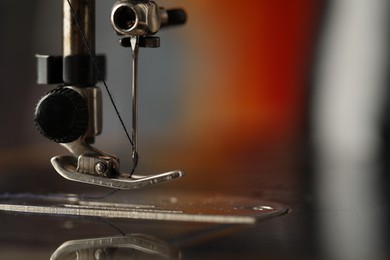 Photo of Sewing machine with thread on blurred background, macro view. Space for text