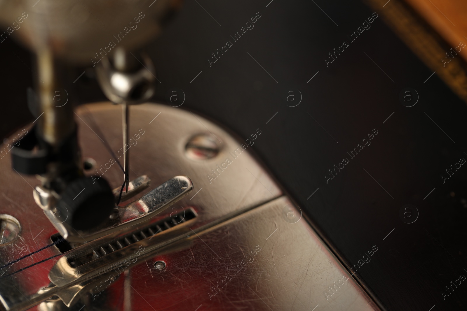 Photo of Sewing machine with thread on dark background, macro view. Space for text