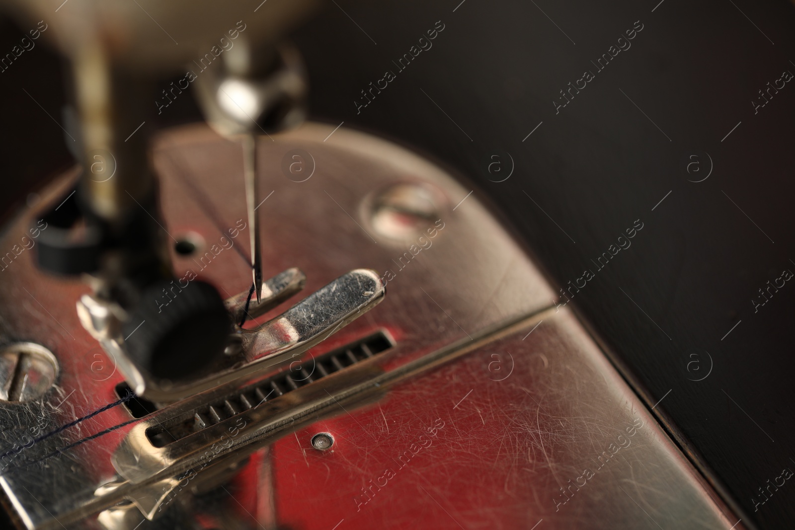 Photo of Sewing machine with thread on dark background, macro view. Space for text