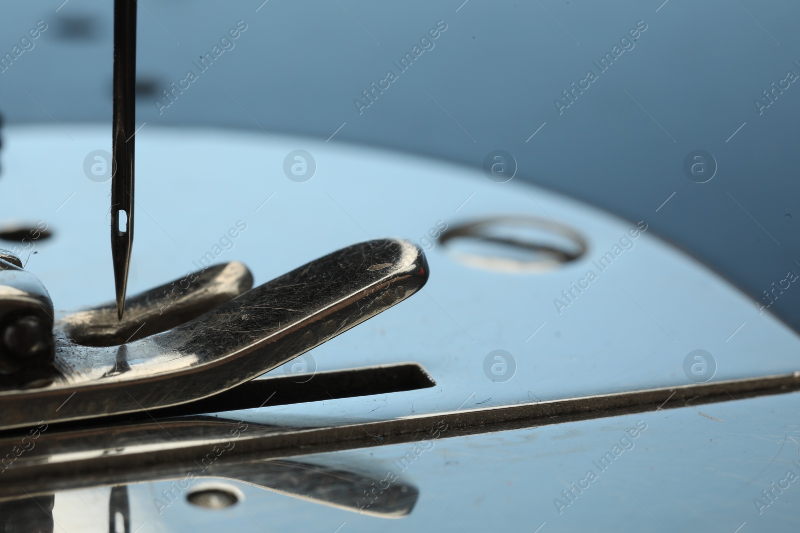 Photo of Sewing machine on light blue background, macro view. Space for text