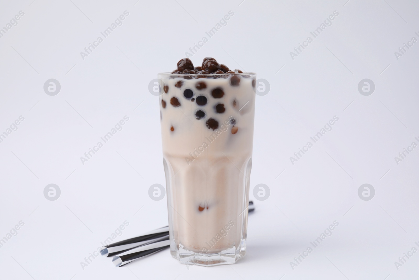 Photo of Tasty milk bubble tea in glass and straws on white background