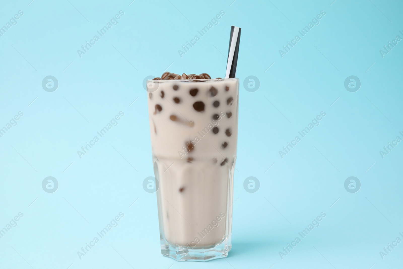 Photo of Tasty milk bubble tea in glass on light blue background