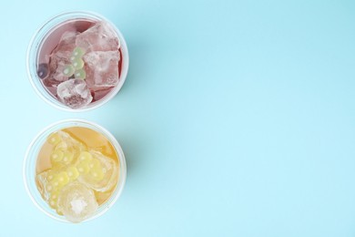 Photo of Tasty bubble tea in plastic cups on light blue background, flat lay. Space for text