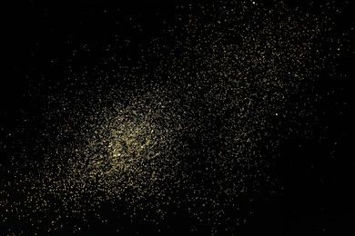 Photo of Beautiful shiny golden glitter on black background, top view