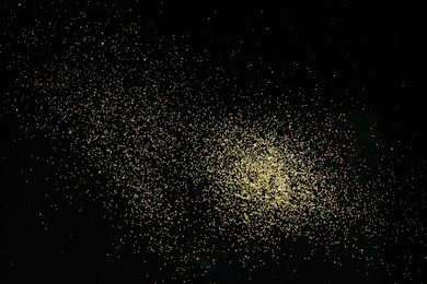 Photo of Beautiful shiny golden glitter on black background, top view