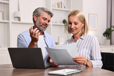 Photo of Pension savings. Couple planning budget at table indoors