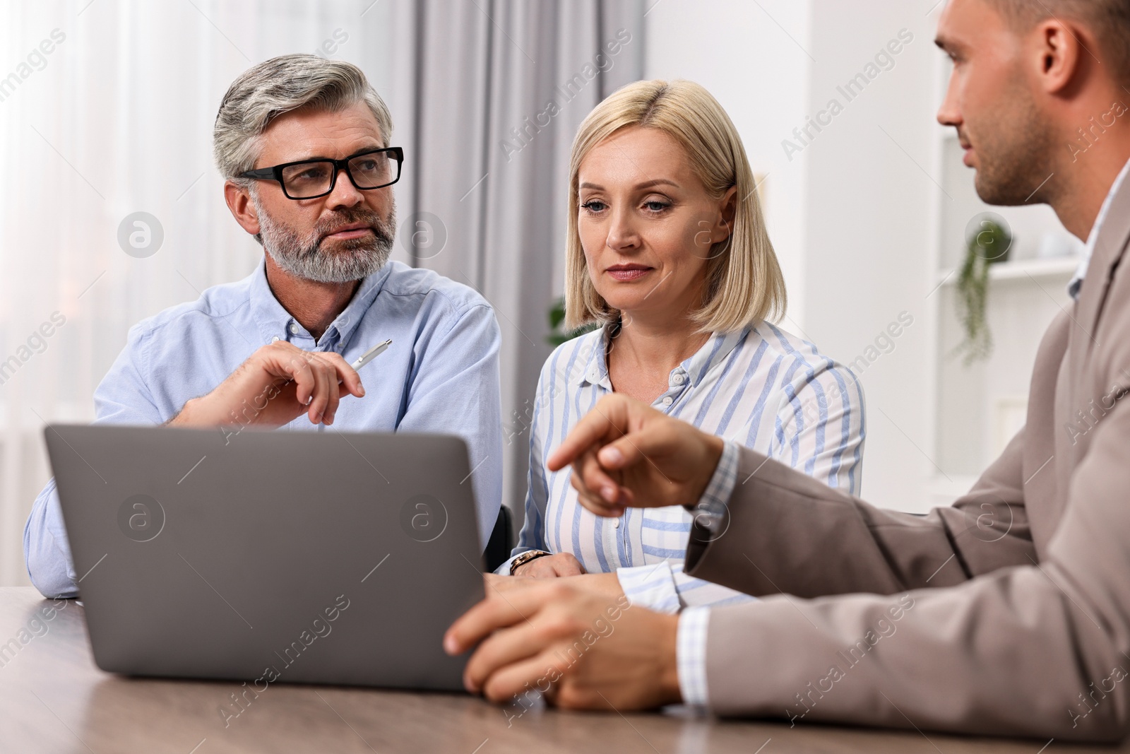 Photo of Pension plan. Couple consulting with insurance agent at table indoors