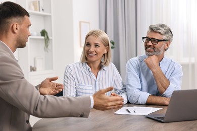 Pension plan. Couple consulting with insurance agent at table indoors