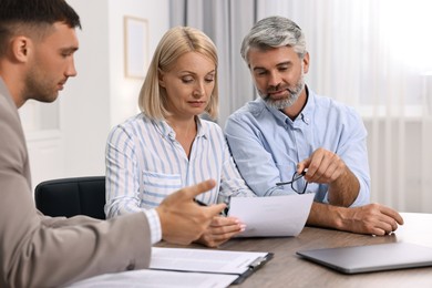 Pension plan. Couple consulting with insurance agent at table indoors