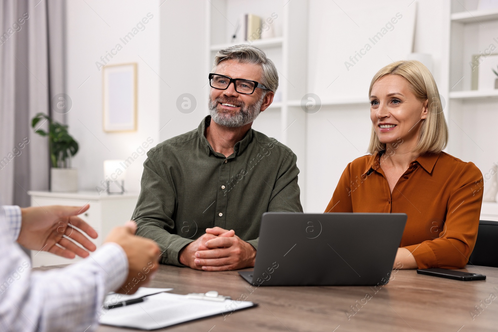 Photo of Pension plan. Couple consulting with insurance agent at table indoors