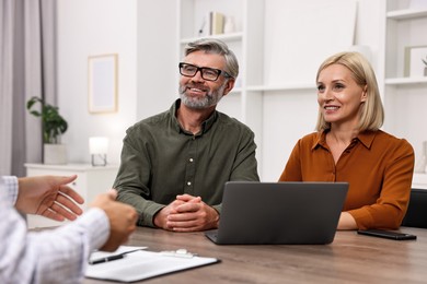 Pension plan. Couple consulting with insurance agent at table indoors