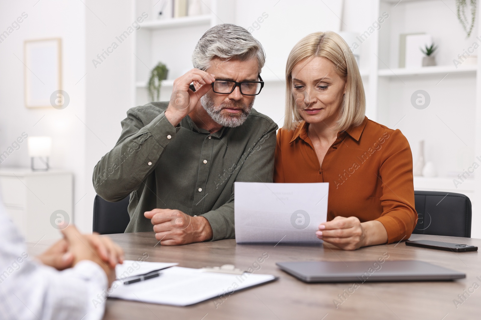 Photo of Pension plan. Couple consulting with insurance agent at table indoors