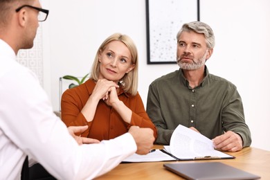 Photo of Pension plan. Couple consulting with insurance agent at table indoors