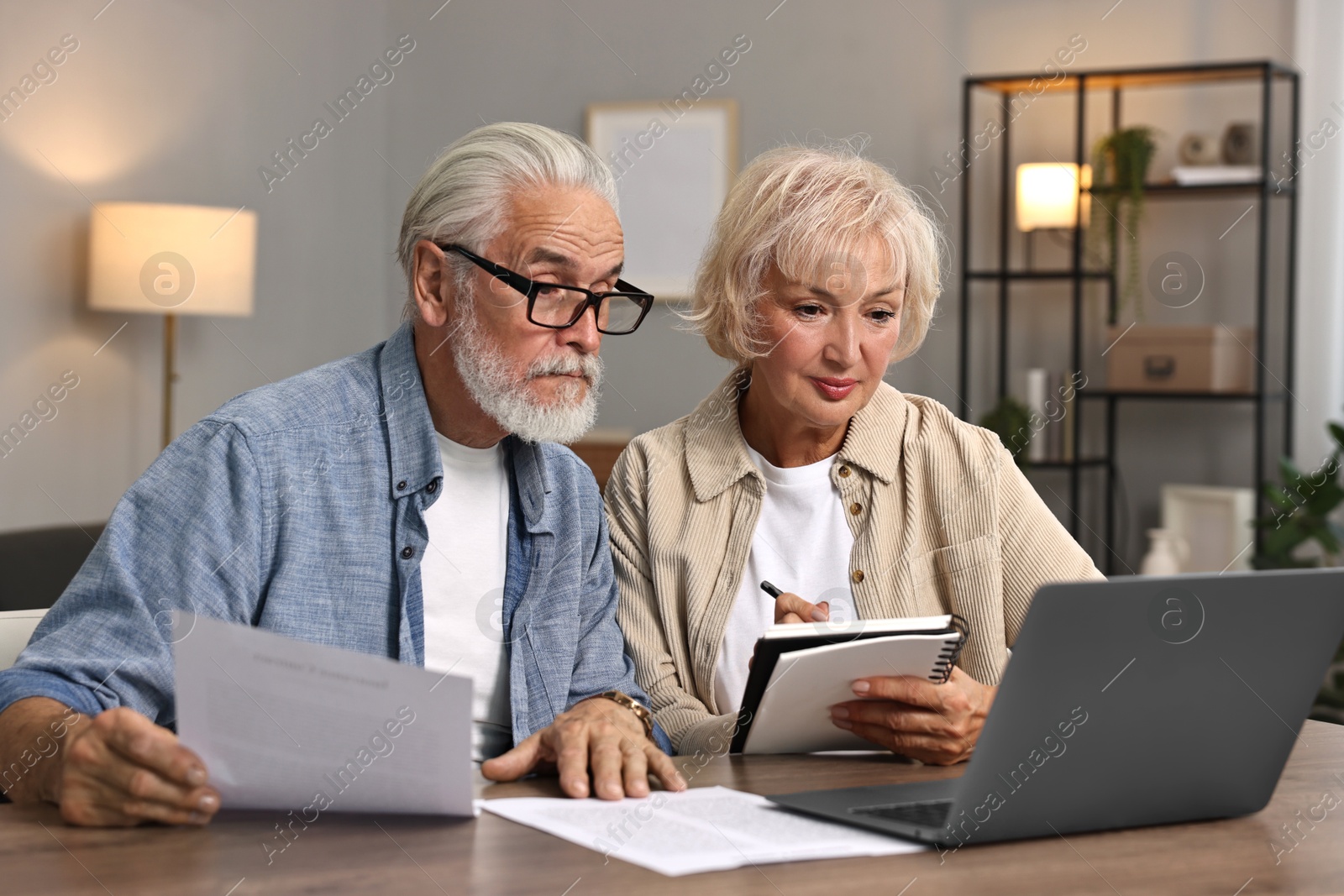 Photo of Pension savings. Senior couple planning budget at wooden table indoors